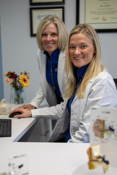 Dr. Rosinko and Dr. O'Connor smiling while using the computer together in the office